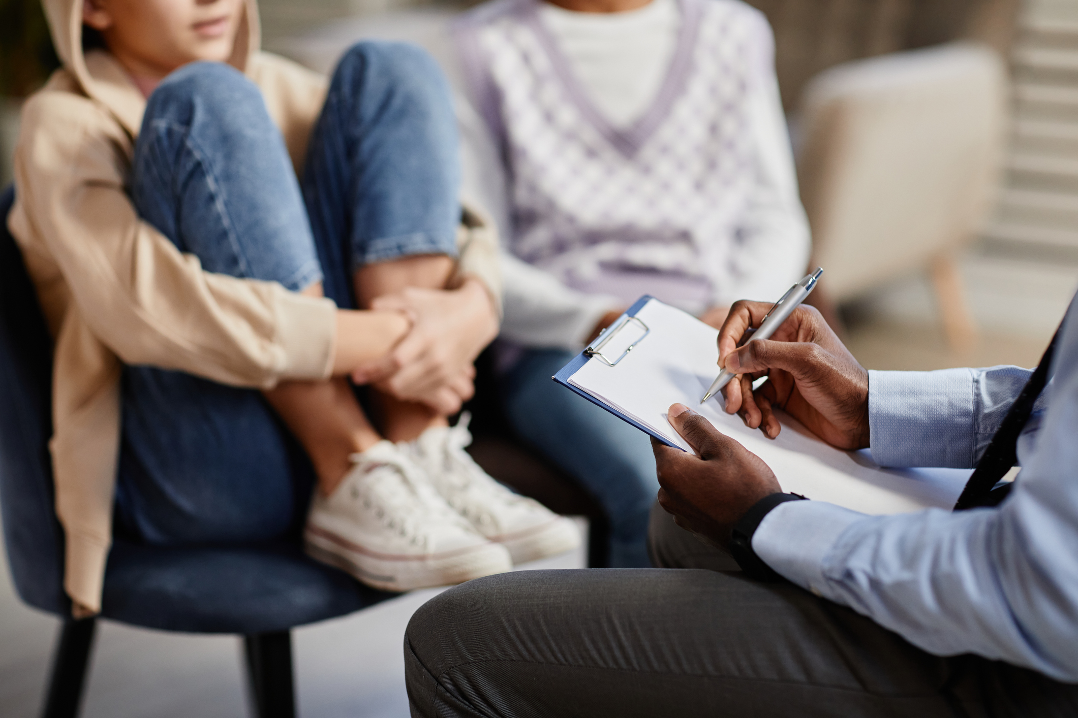 Child sitting with a parent in a mental health provider's office receiving a screening from the provider.