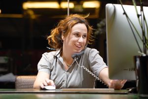 Individual talking on phone while looking at computer